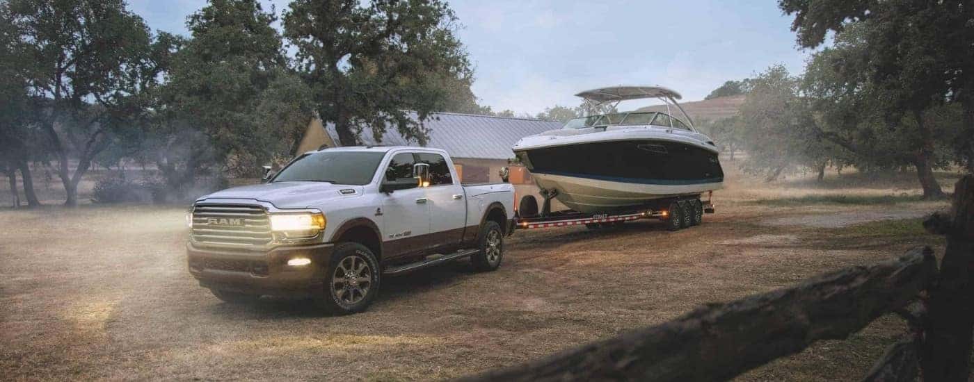 A white 2024 Ram 2500 is shown from the front at an angle while towing a boat.