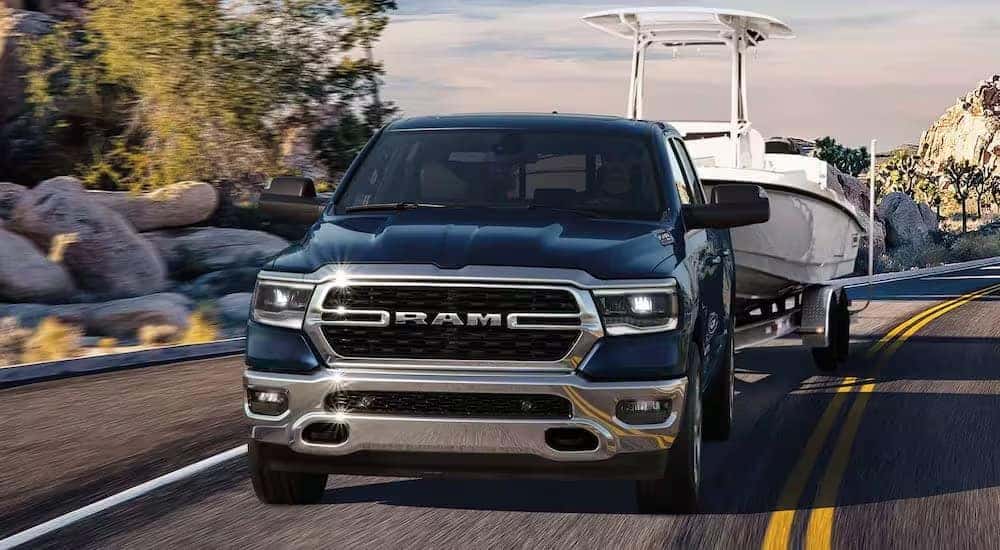 A blue 2024 Ram 1500 Big Horn is shown towing a boat after viewing Ram trucks for sale near Concord.