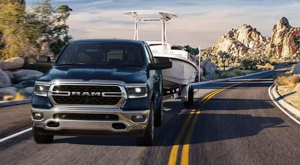 A blue 2024 Ram 1500 Tradesman is shown towing a boat to view Ram trucks for sale near Statesville.