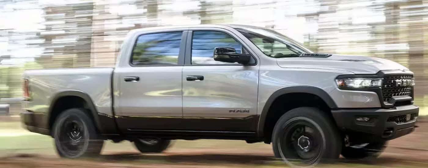 A white 2024 Ram 1500 driving from a dealer with Ram trucks for sale near Concord.