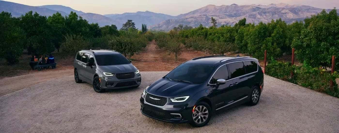 A grey and a black 2023 Chrysler Pacifica are shown from the front at an angle.