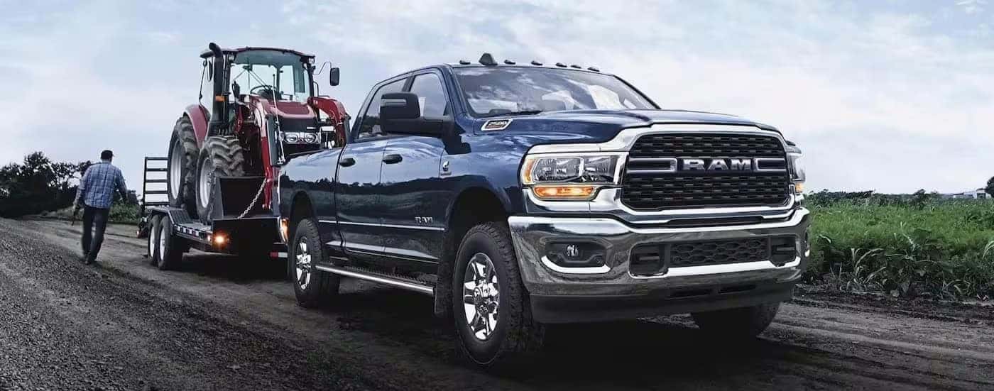 A blue 2024 Ram 2500 Laramie is shown towing a trailer.