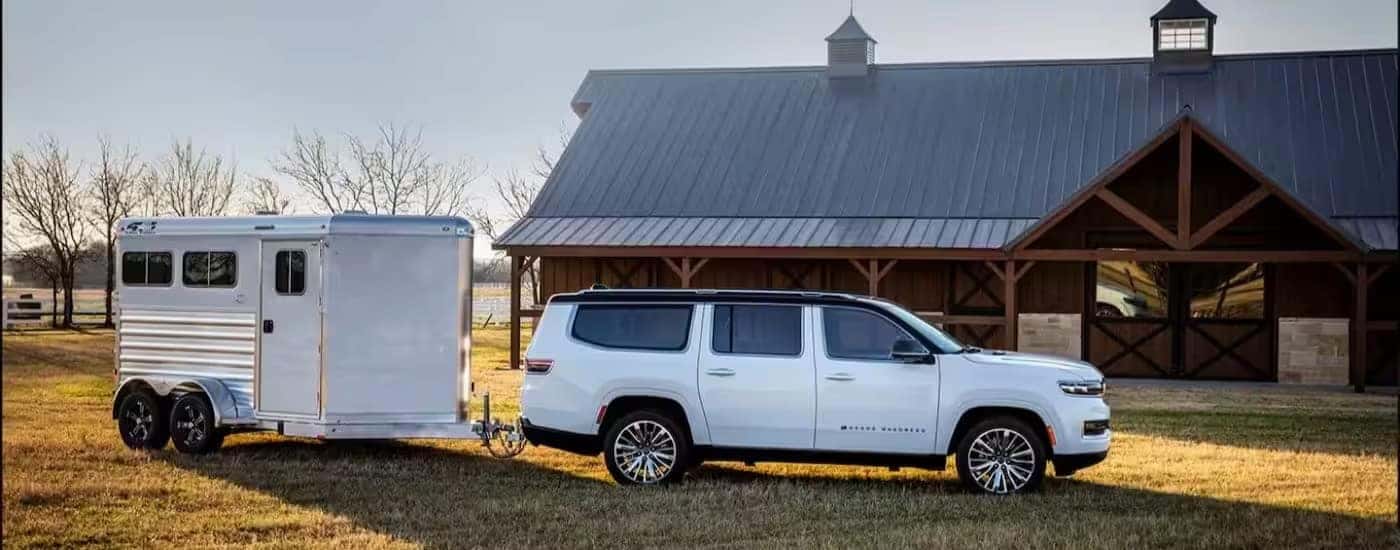 A white 2024 Jeep Grand Wagoneer is shown parked near a barn.