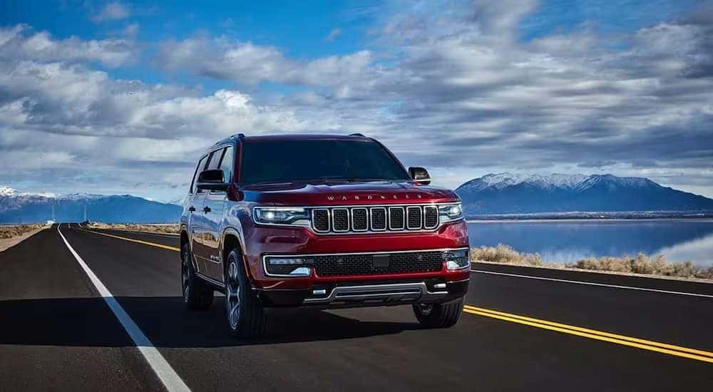 A red 2024 Jeep Wagoneer for sale is shown driving on a highway.