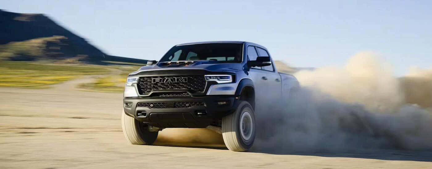 A silver 2025 Ram 1500 RHO kicking up dust while off-roading.