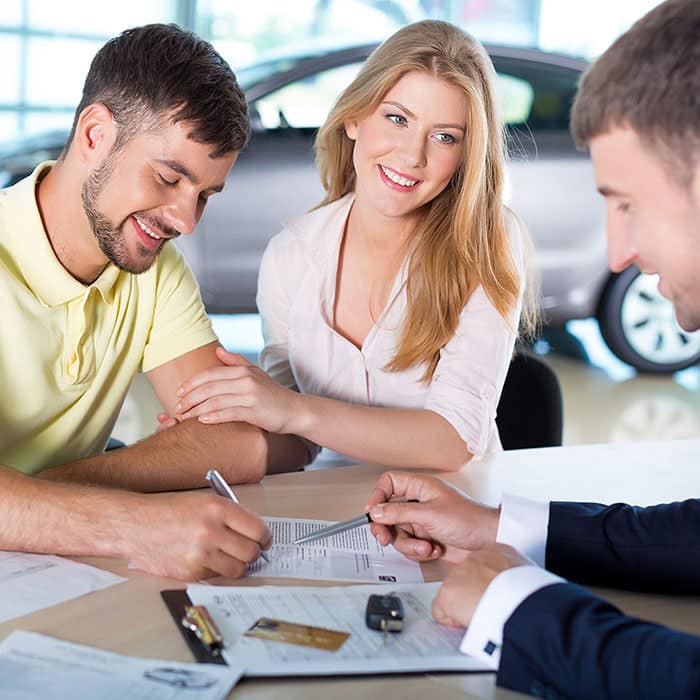 Couple signs paperwork to buy a car