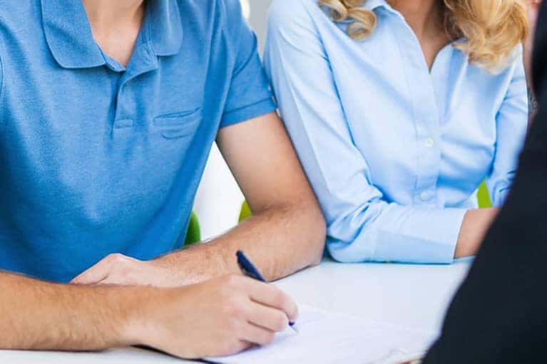 two people looking at and signing papers