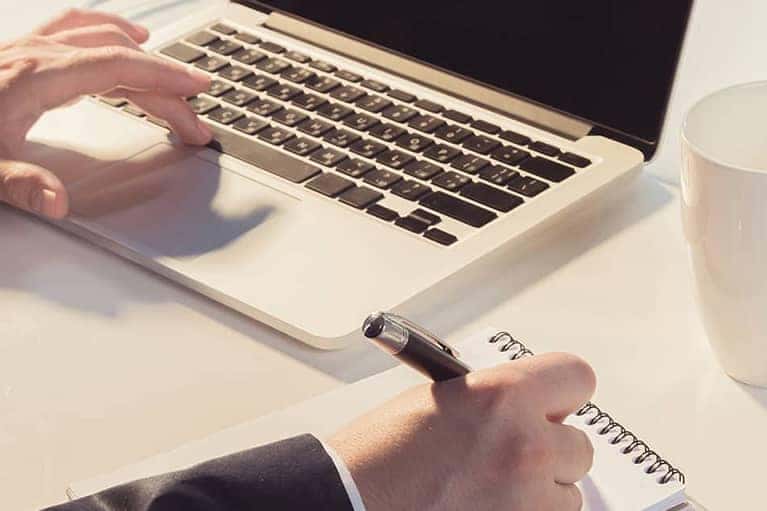 Typing On Keyboard And Pad Of Paper
