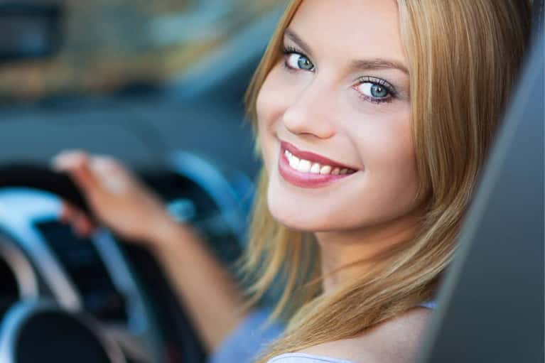 smiling-woman-in-car-gives-thumbs-up-mobile