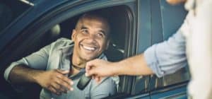 Salesperson giving car keys to new owner through driver's side window in their new Acura