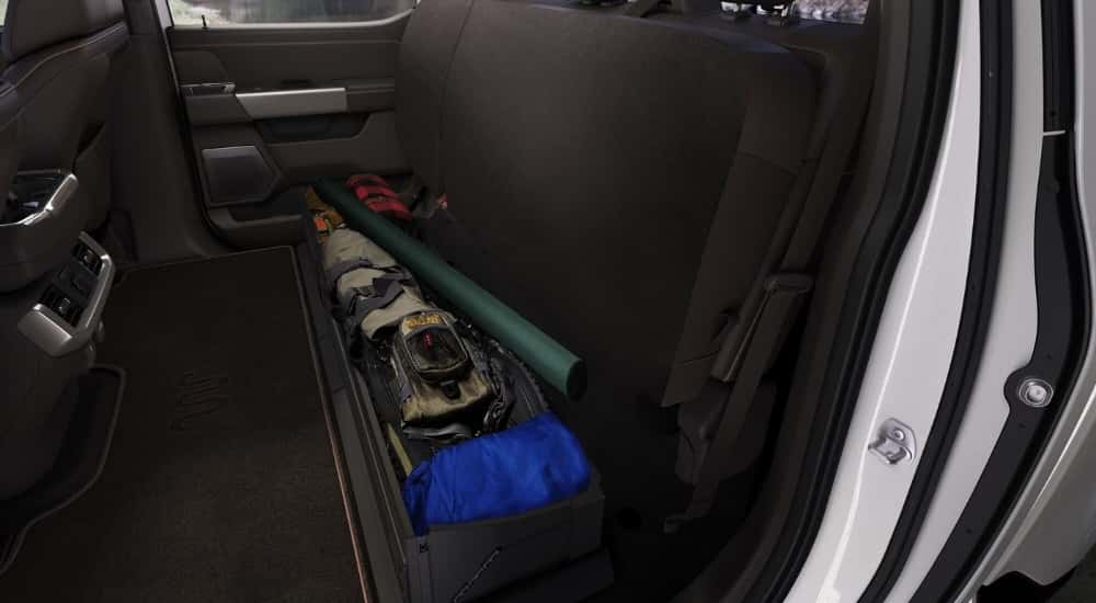 A close-up shows under seat storage in a white 2021 Ford F-150.