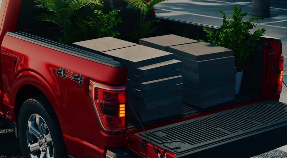 A close-up shows pavers in the bed of a red 2021 Ford F-150.