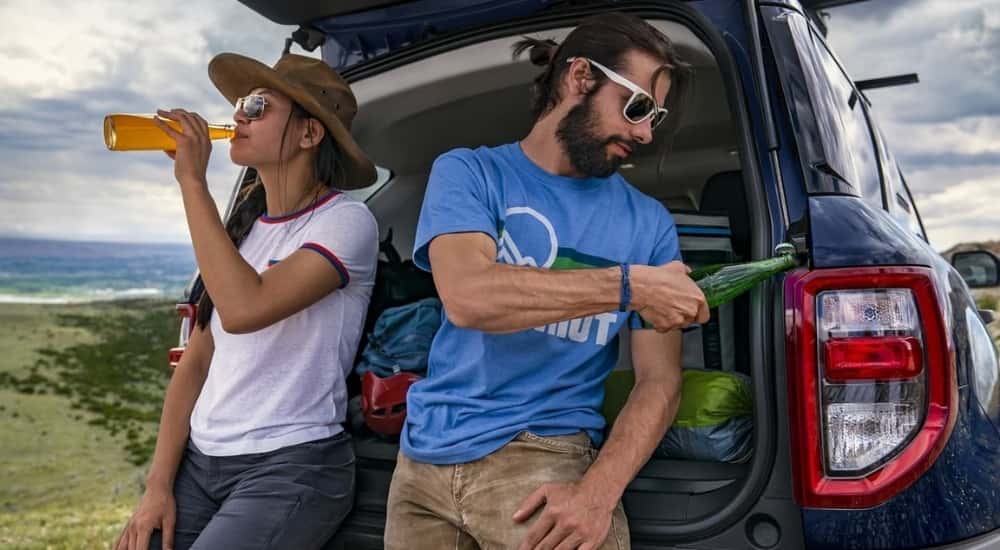 People are shown drinking beverages near a blue 2022 Ford Bronco Sport.