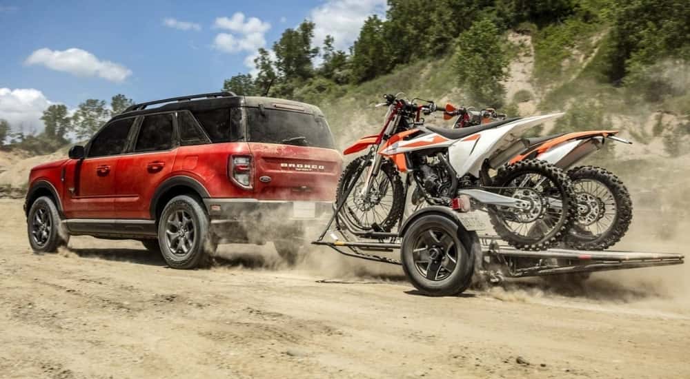 A red 2021 used Ford Bronco Sport for sale is shown towing dirt bikes.