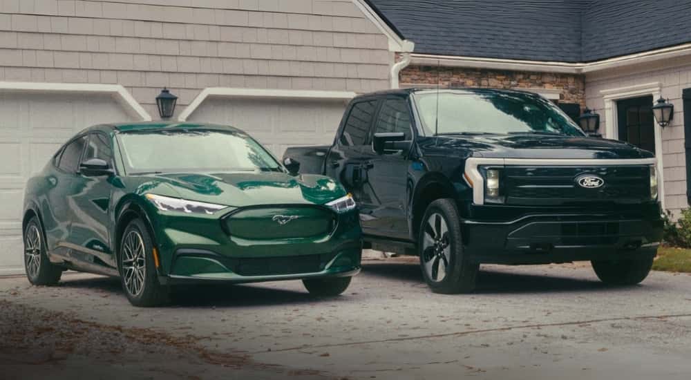 A green  2023 Ford Mustang Mach-E and a black F-150 Lightning are shown parked on a driveway.