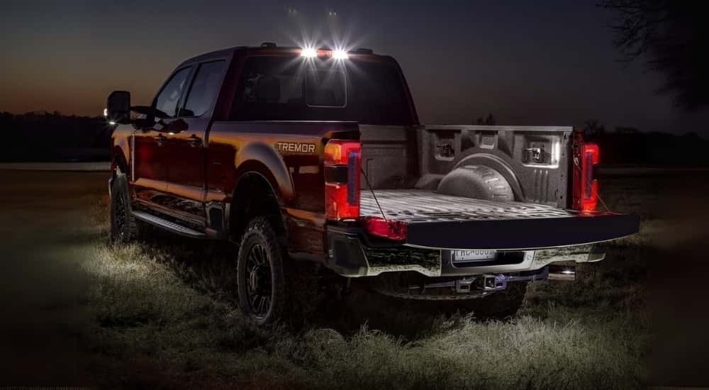 A red  2023 Ford F-250 Lariat Tremor is shown on a clearing at night.
