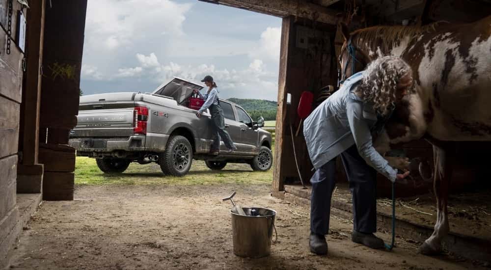 A silver 2023 Ford F-250 Platinum is shown near a barn.