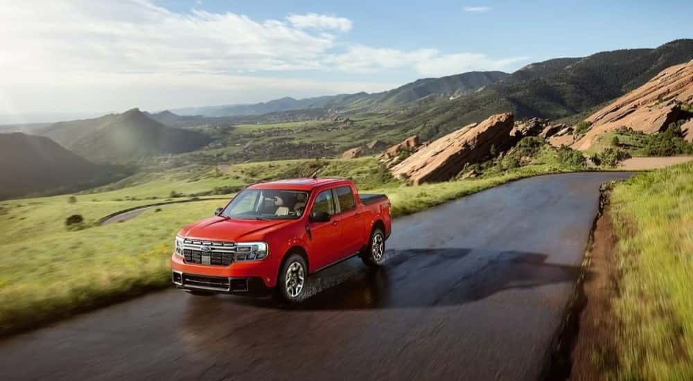 A red 2024 Ford Maverick is shown driving near mountains after leaving a Ford dealer near Winder.