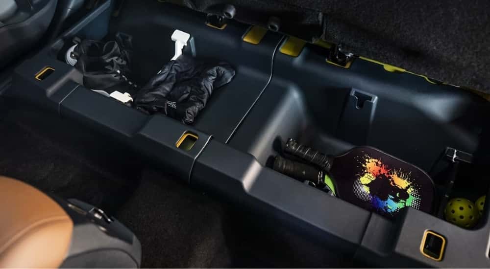 Under seat storage is shown in a yellow 2024 Ford Maverick.