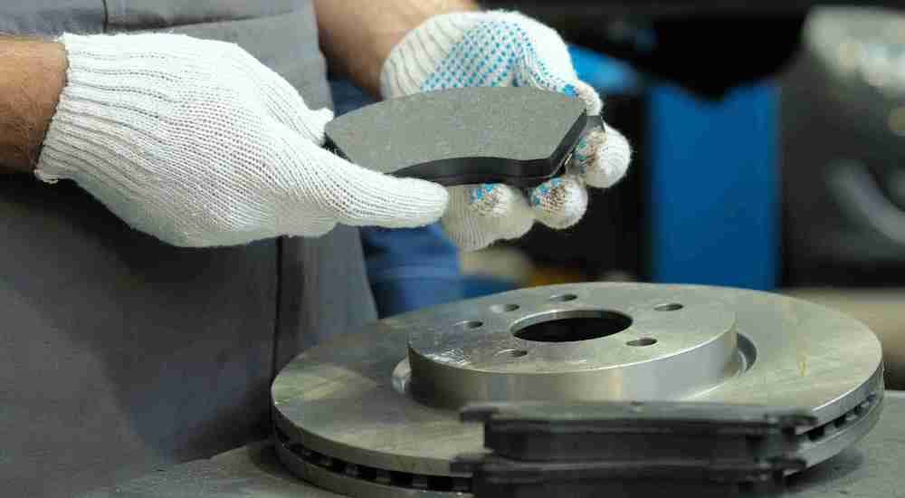 A mechanic is shown holding up a brake pad at an auto repair shop near McDonough.