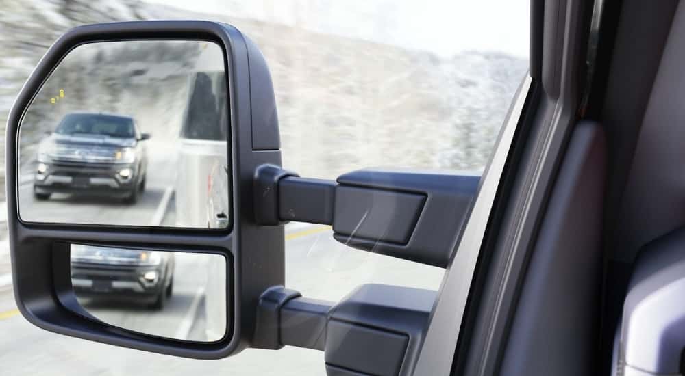 A blind sport monitoring icon is shown on the mirror of a silver 2023 Ford F-150.