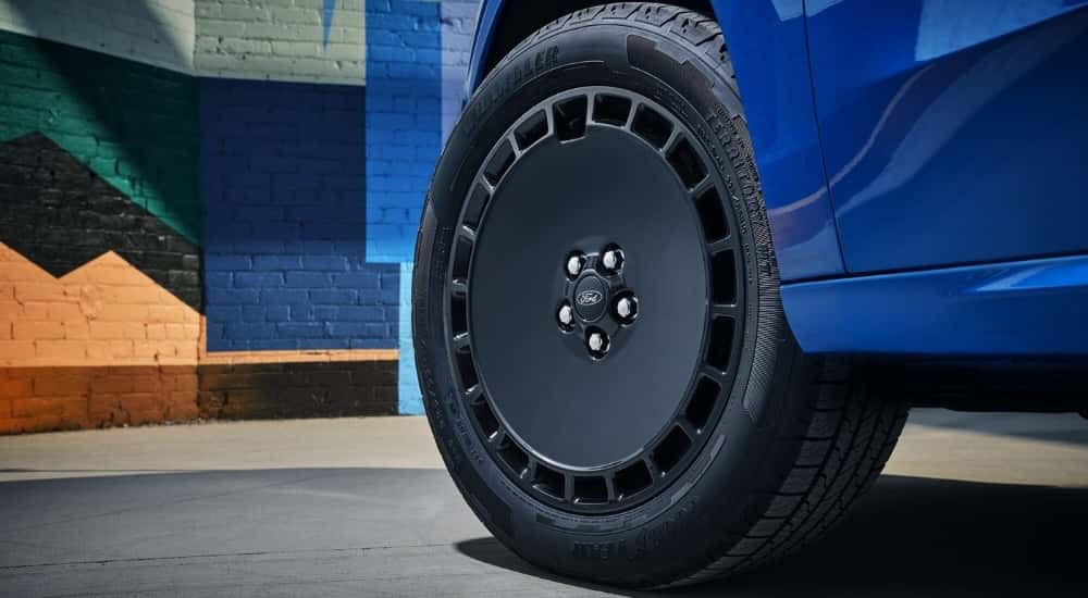 A close up shows a black wheel on a blue 2025 Ford Maverick Lobo.