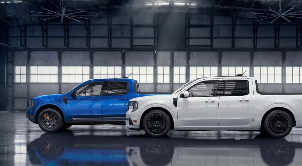 A blue 2025 Ford Maverick Tremor and white Maverick Lobo are parked in a garage.