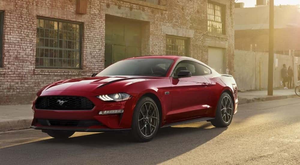 A red 2022 Ford Mustang is parked on the side of a city street after viewing used cars for sale.