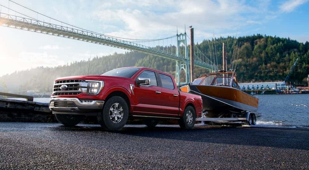 A red 2022 Ford F-150 Lariat pulling a boat out of a lake.