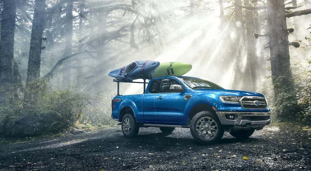 A blue 2022 Ford Ranger Lariat parked in the woods with kayaks.