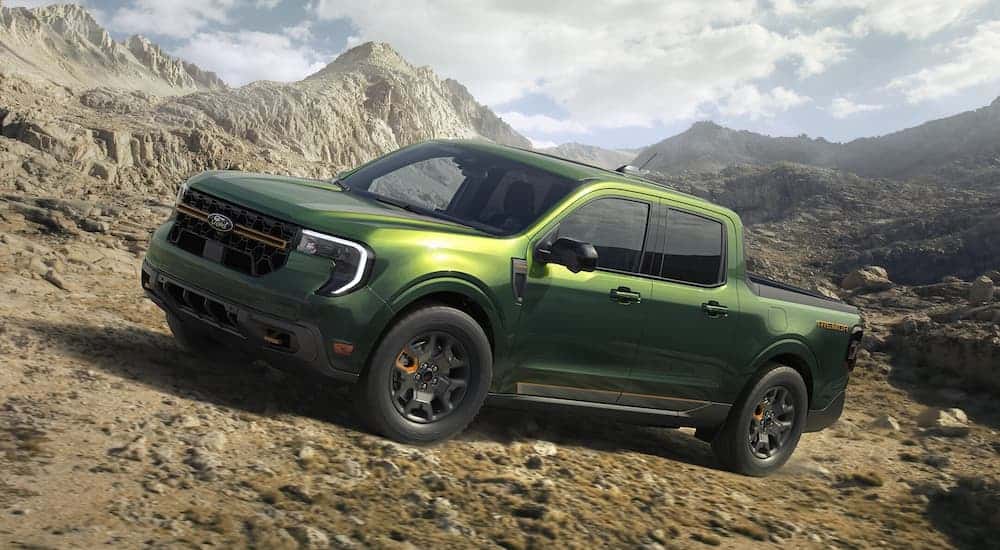 A green 2025 Ford Maverick Tremor driving off-road up a dirt hill.