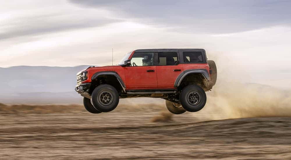 An orange 2025 Ford Bronco Raptor is shown from the side.