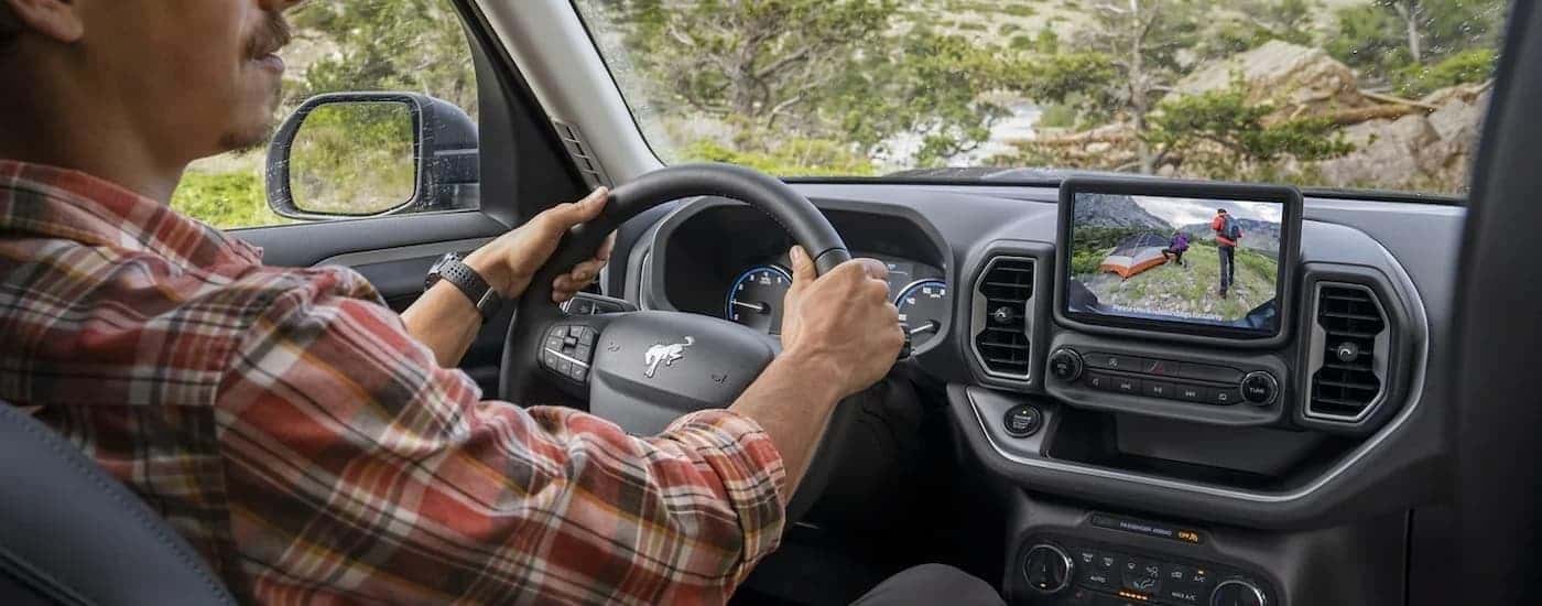 A man is shown driving in a 2023 Ford Bronco Sport on a remote trail.
