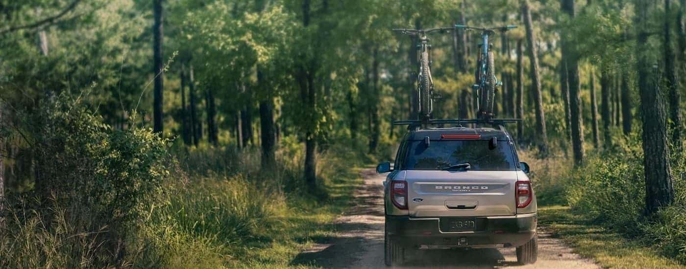 A grey 2023 Ford Bronco Sport is shown from the rear on a dusty dirt road.