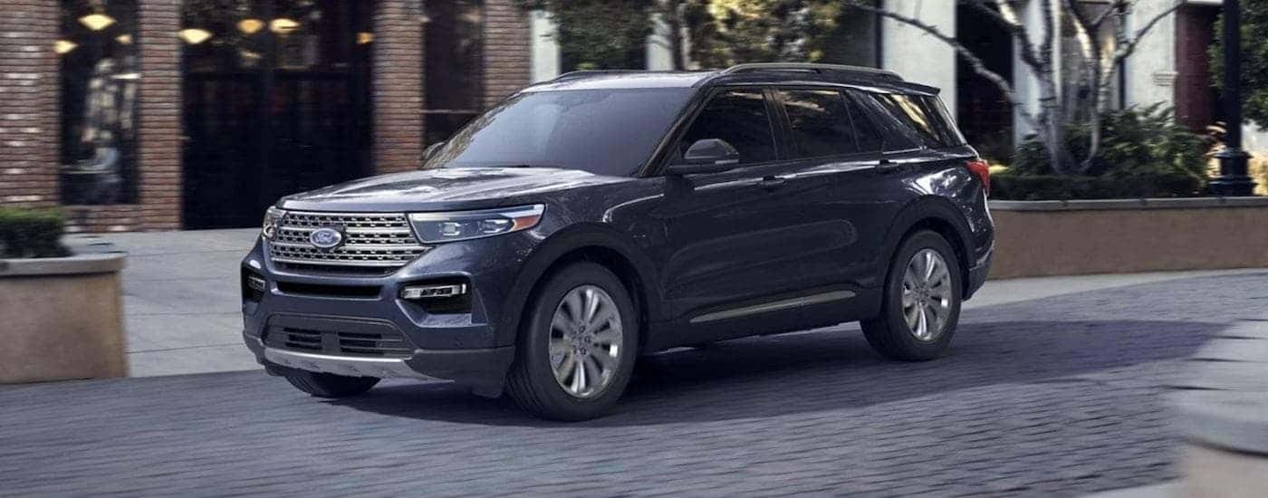 A blue 2023 Ford Explorer is shown from the side in front of a building.
