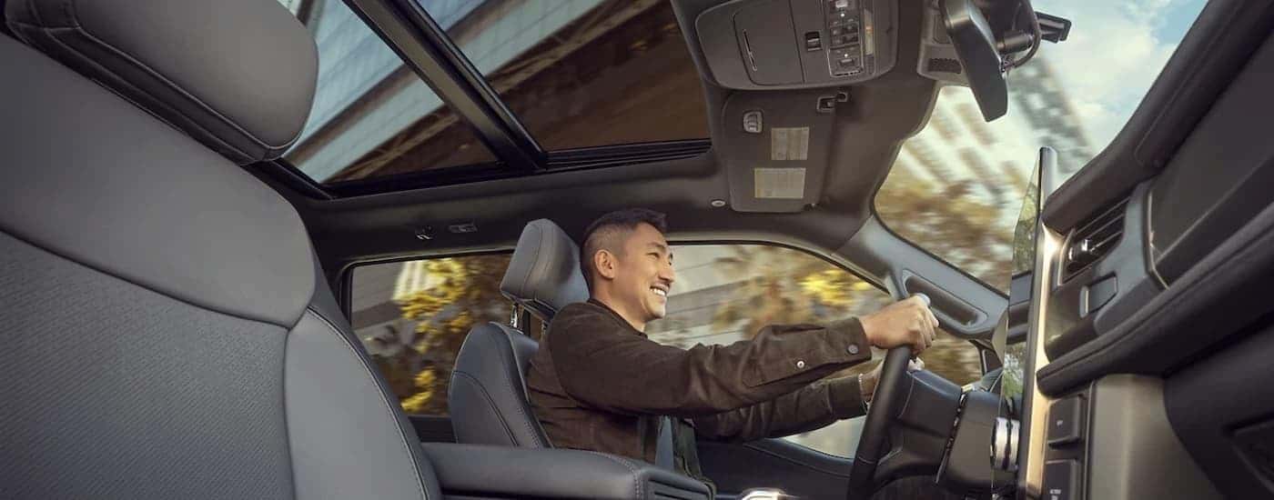 A man is shown driving a 2023 Ford F-150 Lightning on a city street.