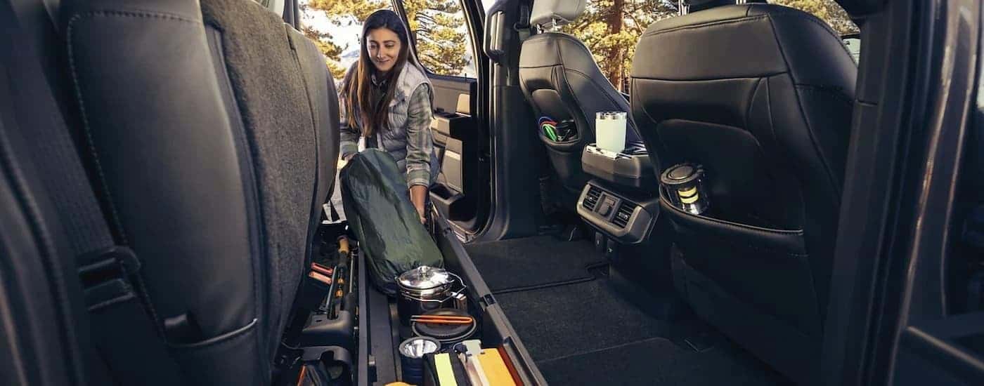A woman is shown using the underseat storage in a 2023 Ford F-150 Lightning.