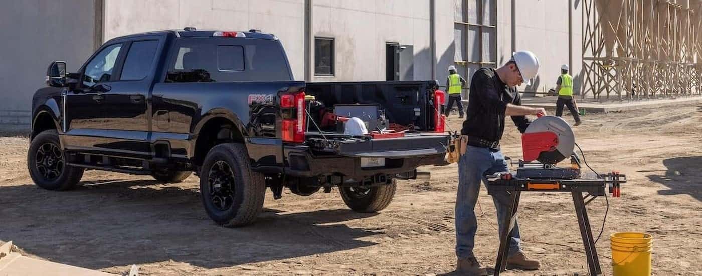 A black 2023 Ford F-250 Super Duty XL STX is shown from the rear on a construction site.