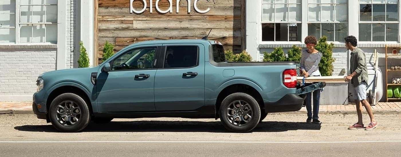 A blue 2023 Ford Maverick is shown from the side being loaded with boards.