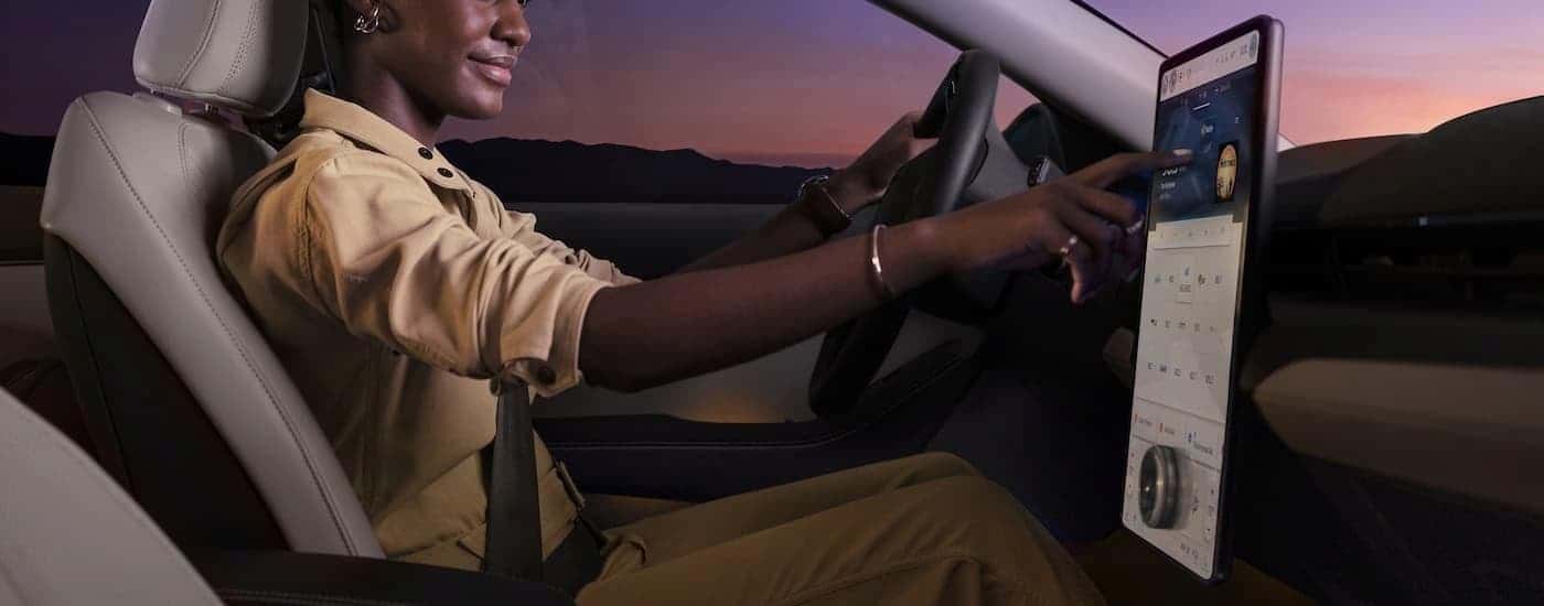 A woman is shown using the infotainment screen in a 2023 Ford Mustang Mach-E.