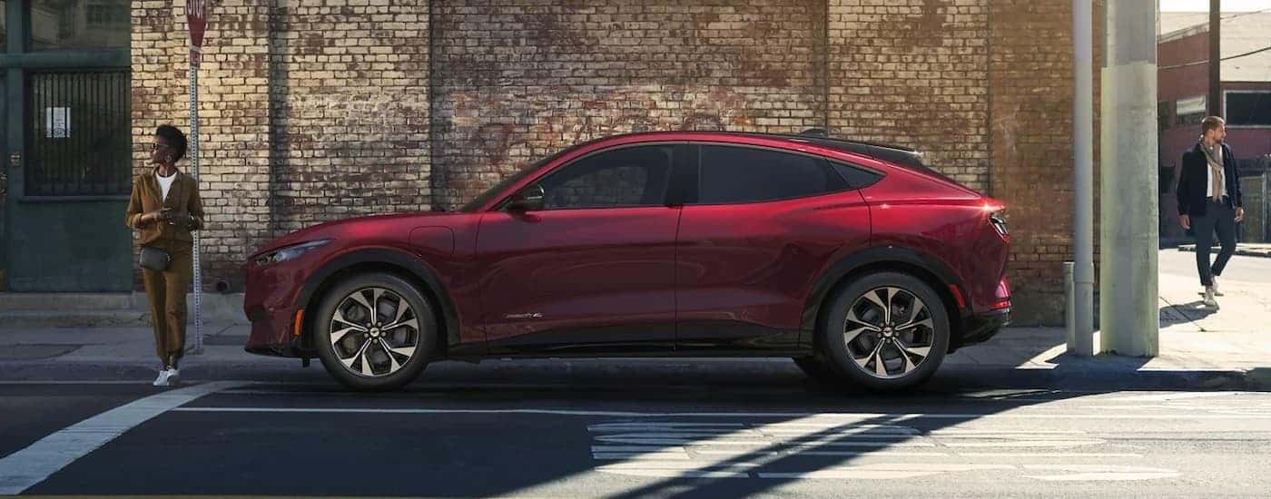 A red 2023 Ford Mustang Mach-E is shown from the side of a city street.