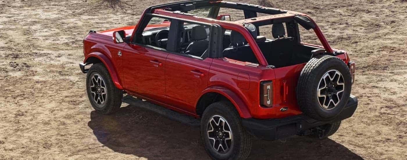A rear view of a red 2024 Ford Bronco Outer Banks parked on dirt.