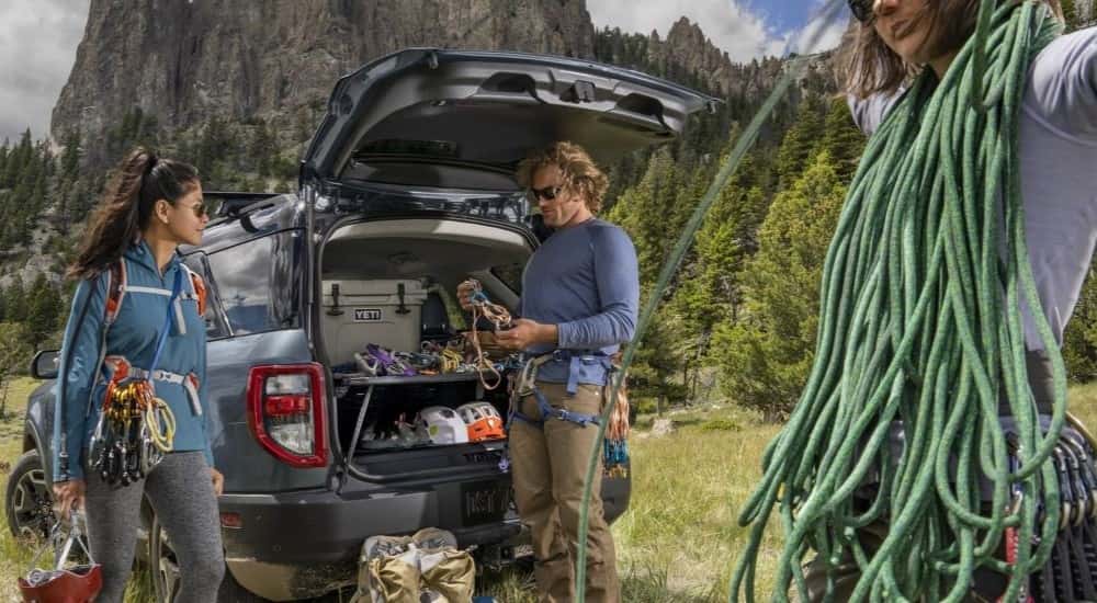 Three mountain climbers are shown near a blue 2024 Ford Bronco Sport.