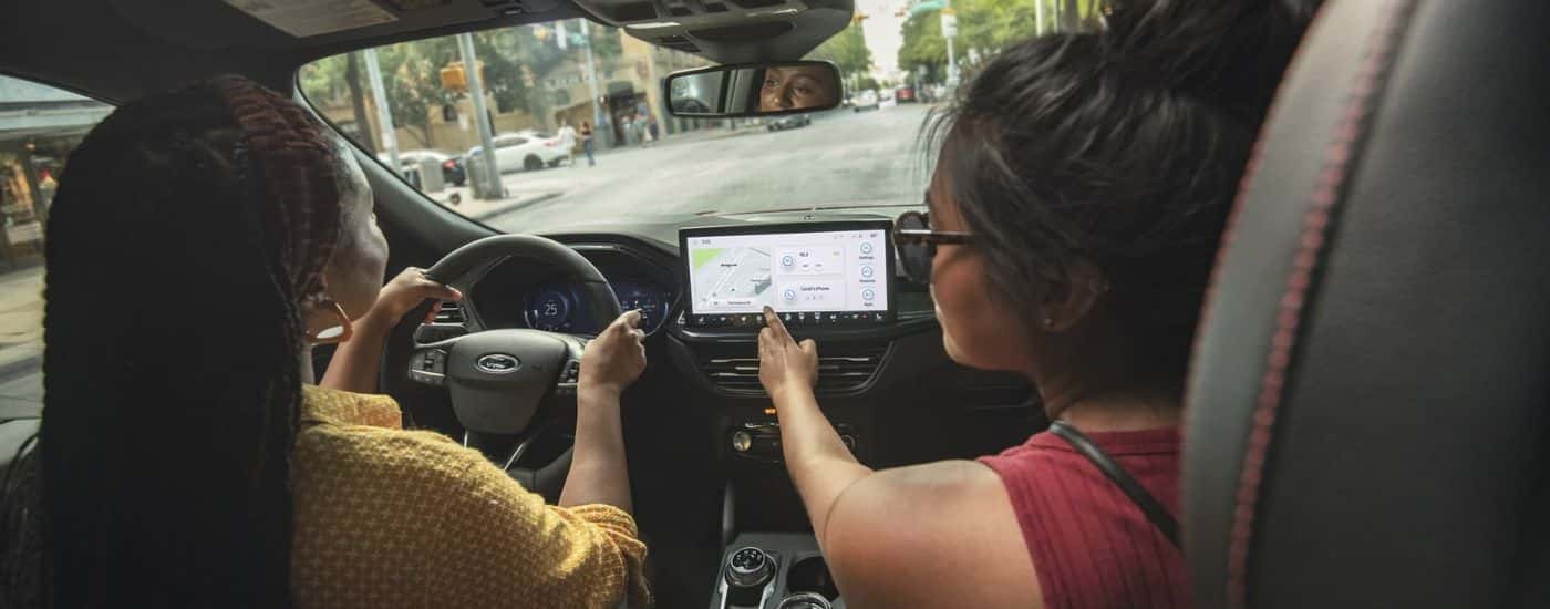 Two friends are shown using the infotainment screen in a 2024 Ford Escape to navigate a city.