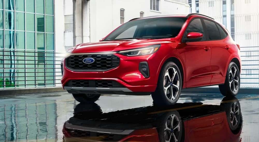 A red 2024 Ford Escape ST-Line is shown parked near city buildings.