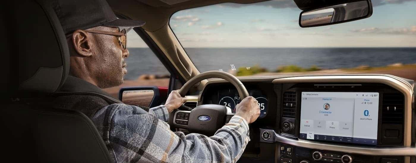 A man is shown driving a 2024 Ford F-150 on an open road.
