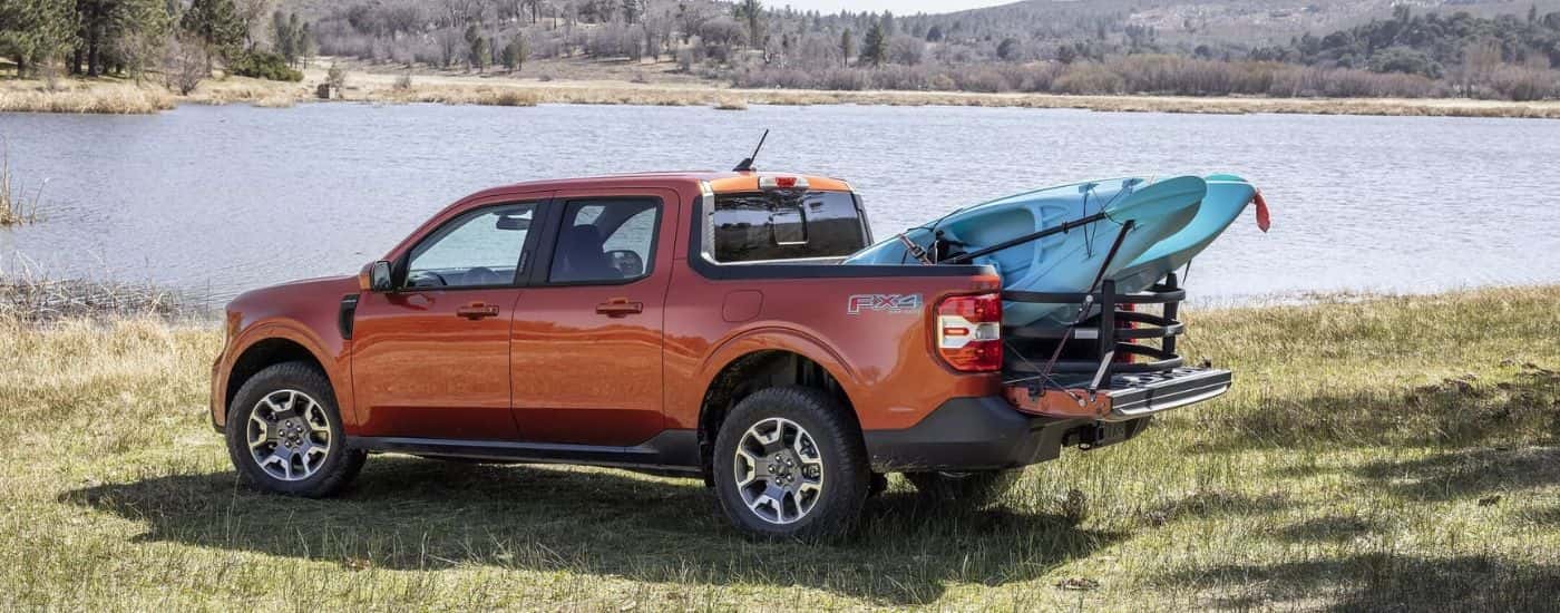 A red 2024 Ford Maverick Lariat is shown from the side with a kayak in the bed.