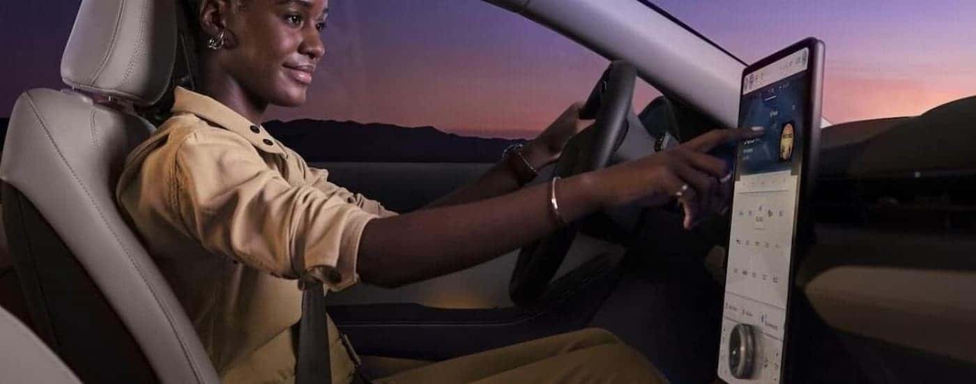 A person is shown using the infotainment screen in a 2024 Ford Mustang Mach-E.