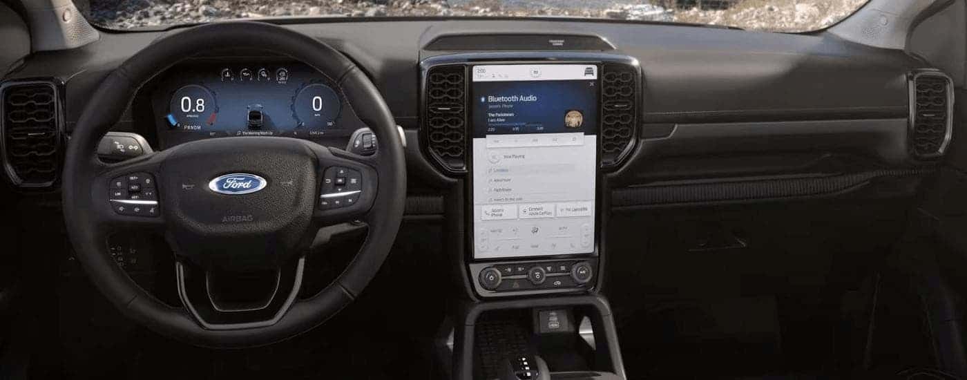 The black dashboard of a 2024 Ford Ranger shows the steering wheel and infotainment screen.