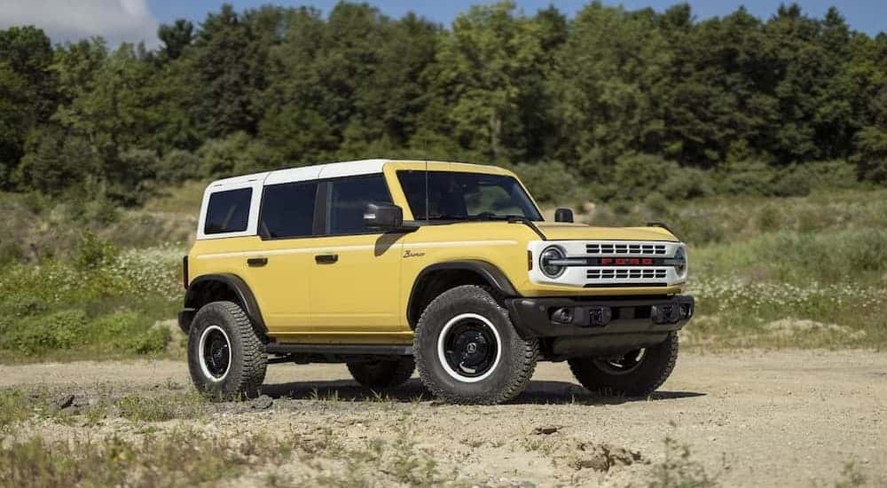 A yellow 2024 Ford Bronco Heritage Limited Edition is shown parked off-road.